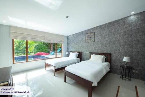 a bedroom with two beds and a large window at Pool Villas by Honey - Luxury Family Resort-8 km from Beach & Nightlife in Nong Prue