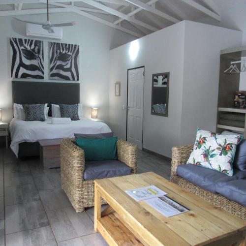 a living room with a bed and a table and chairs at Villa de Leeu, Perfect for Two in Marloth Park