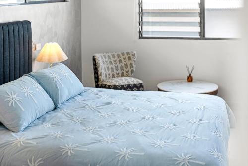 a bedroom with a blue bed with a lamp and a chair at Stunning Ocean-View Home, Walk to Village & Beach in Sawtell