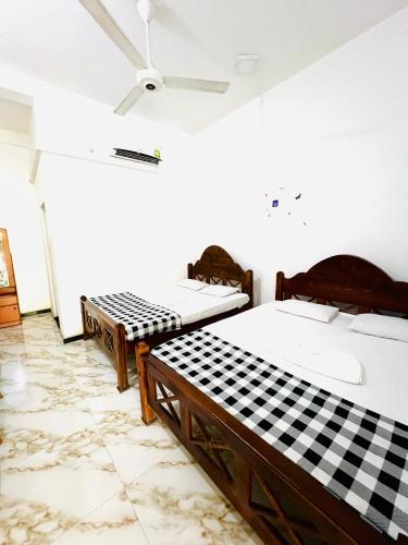 three beds in a room with a ceiling fan at Monkey Garden Hotel in Polonnaruwa