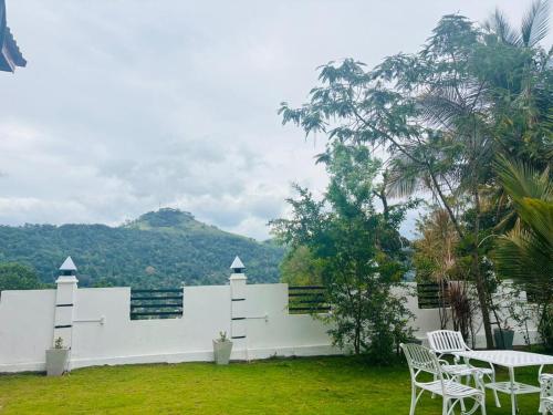 Un edificio blanco con una mesa y sillas en un patio. en Spring View Holiday Home - Villa, en Badulla