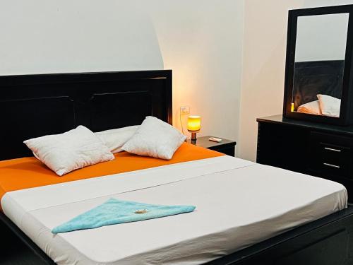 - une chambre avec un lit doté d'une couverture orange et d'un miroir dans l'établissement Luxor Adventure Guest House, à Al Aqālitah