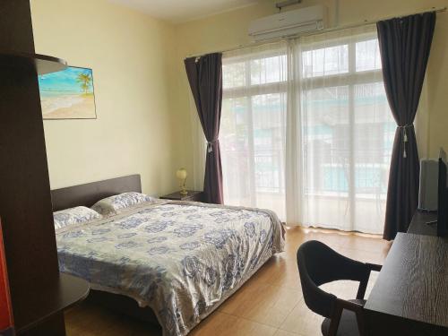 a bedroom with a bed and a large window at Belle Mare Apartment in Belle Mare