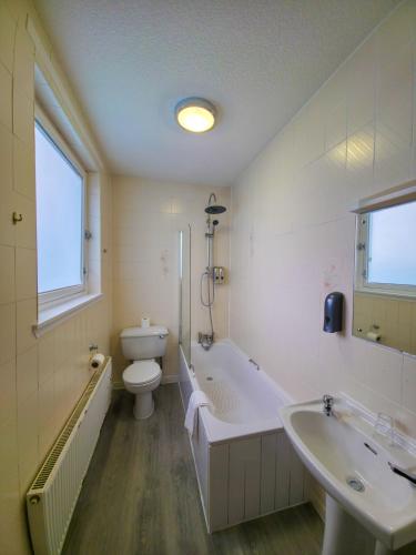a bathroom with a tub and a toilet and a sink at Lovat Hotel in Perth