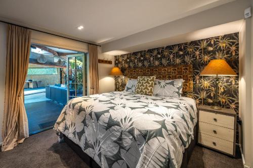 a bedroom with a bed and a large window at Kauri Springs Lodge still the same beautiful place but so so much better in Waiheke Island