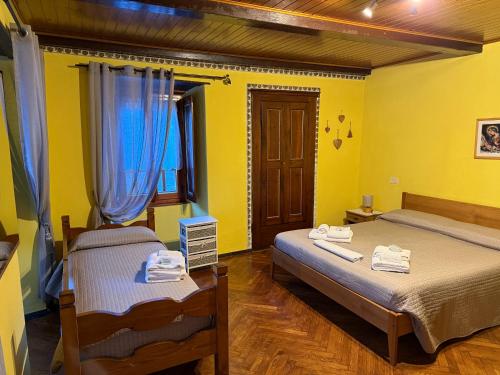two beds in a room with yellow walls at Il Camino in Anzino