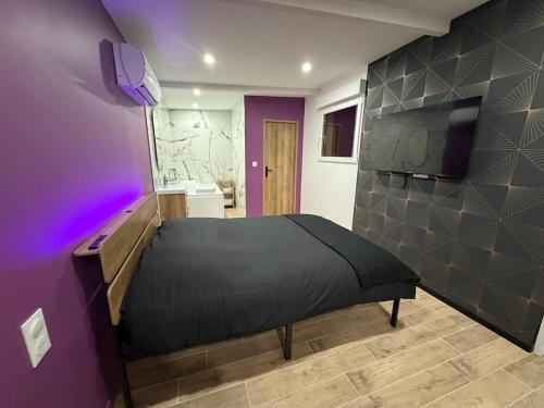 a bedroom with a bed and a purple wall at Les secrets de l Esch in Jezainville