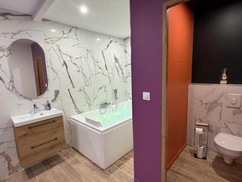 a bathroom with a tub and a sink and a toilet at Les secrets de l Esch in Jezainville