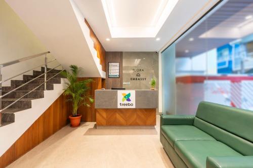 a lobby with a green couch and stairs at Treebo Flora Embassy in Chennai