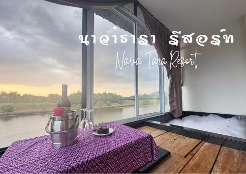 a table with a bottle of wine and a window at Nava Tara Resort in Takua Pa