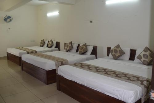 a group of three beds in a room at Sri Darshini Comfort 2kms from Hinkal Flyover in Mysore