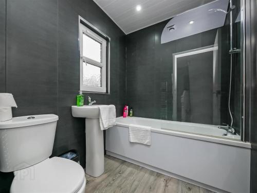 a bathroom with a toilet and a tub and a sink at 4br House Popular Ravenhill Road in Belfast