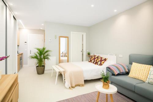 een slaapkamer met een bed en een blauwe bank bij Apartamentos La Gringa Centro Gijon I Obra nueva con posibilidad de Parking in Gijón