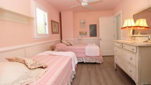 Dos camas en una habitación con paredes rosas y un lavabo. en Dunescape, en West Cape May
