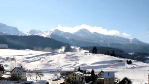 ein schneebedeckter Hügel mit Häusern und Bergen im Hintergrund in der Unterkunft Studio chaleureux avec vue plein sud imprenable ! in Villard-de-Lans