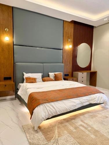 a bedroom with a large bed with a blue headboard at Urban Sage Apartments in Kampala