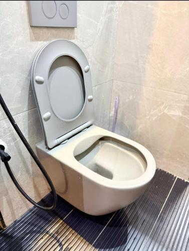 a white toilet with a hose attached to a wall at Urban Sage Apartments in Kampala