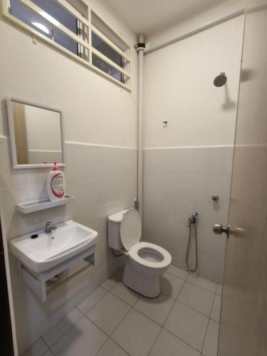a white bathroom with a toilet and a sink at Eiman Homestay in Kuala Terengganu