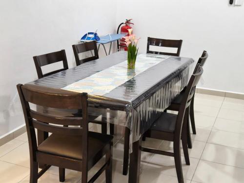 een eettafel met stoelen en een vaas met bloemen erop bij Eiman Homestay in Kuala Terengganu