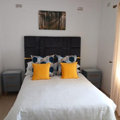 a bedroom with a large bed with yellow pillows at Wales Suite in Harare