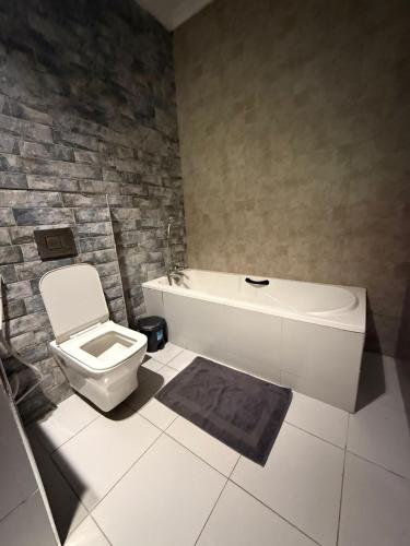 ein Badezimmer mit weißer Toilette und Badewanne in der Unterkunft Hillsgate Experience a Luxury Home in Nairobi in Nairobi