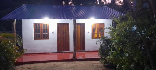 a small house with a blue roof and wooden doors at Batti Relax Point Villa & Rooms in Batticaloa