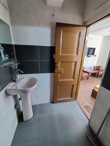 a bathroom with a sink and a wooden door at Hotel Alankar in Manāli