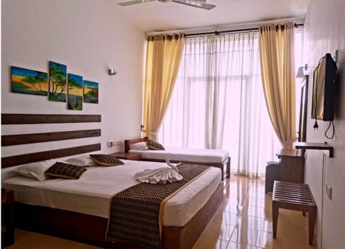 a hotel room with two beds and a television at Ceylan Lodge Anuradhapura in Anuradhapura