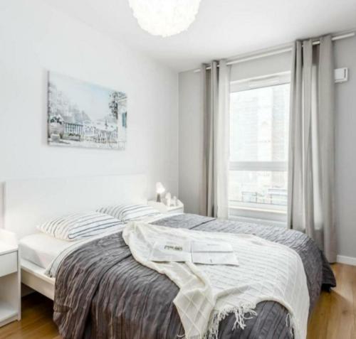 a white bedroom with a bed and a window at Rynek aparts in Wrocław