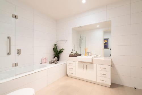 a bathroom with two sinks and a tub and a mirror at Rooftop deck - Central OG - Seaview Luxe in Ocean Grove