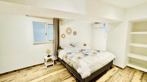 Una habitación blanca con una cama y una ventana en Chez Nat&Jo, en Le Bois de Nèfles