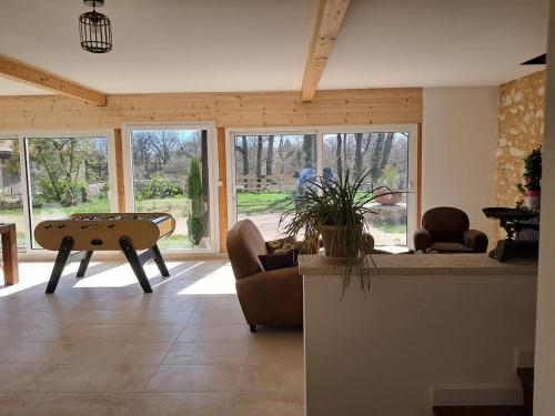 un soggiorno con tavolo, sedie e finestre di Gîte En Gélion a Sarrant