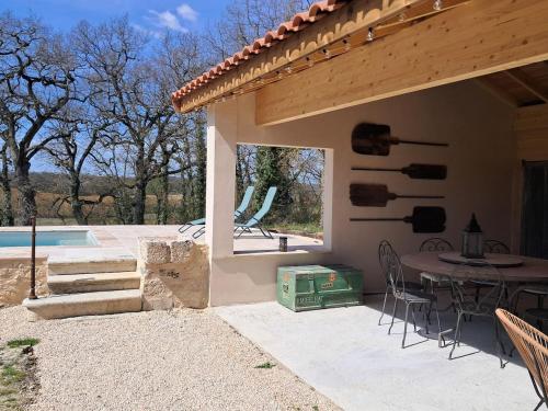 un patio con tavolo e sedie e una piscina di Gîte En Gélion a Sarrant