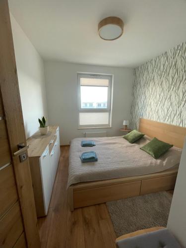 a small bedroom with a bed and a window at Sunny Franciszkanska Nowy apartament 4os 2 min z S6 in Koszalin