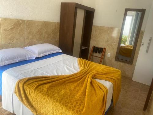 a bedroom with a bed with a yellow blanket on it at Blue Sapphire guest house in Caucaia