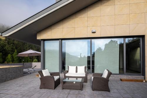 eine Terrasse mit Stühlen, einem Tisch und einigen Fenstern in der Unterkunft Beautiful townhouse 20km from Bilbao in Laudio/Llodio