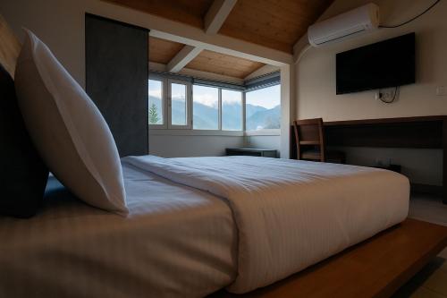 Un dormitorio con una cama grande con una ventana grande. en Brookfield, en Pālampur