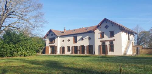 a large white house on a grass field at Aux Domaines d'Automne in Péronnas