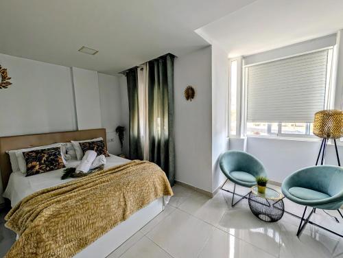 a bedroom with a bed and two chairs and a window at Luxury Bahia Sea Views by Deihu Experiences in Los Cristianos