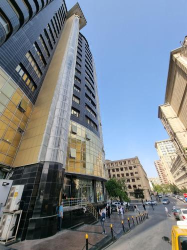 central apartment في باكو: مبنى مرتفع مع أشخاص يمشون أمامه