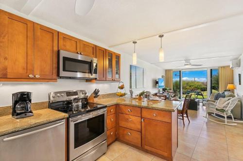a kitchen with stainless steel appliances and a living room at Keawakapu 208 · KKP 208 Renovated Condo w AC Near Beach Shops in Wailea