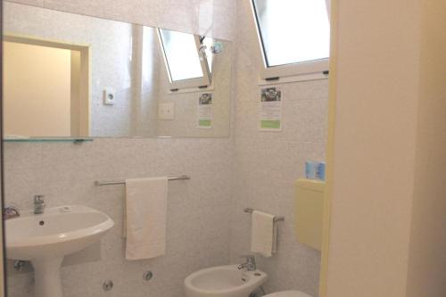 Un baño con lavabo, inodoro y espejo. en Depandance Blue Hotel, en Cesenatico