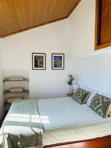 a bedroom with a large bed with two pillows at Casinha da Relva 