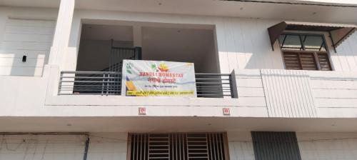a white building with a sign on a balcony at Nangli Homestay in Meerut