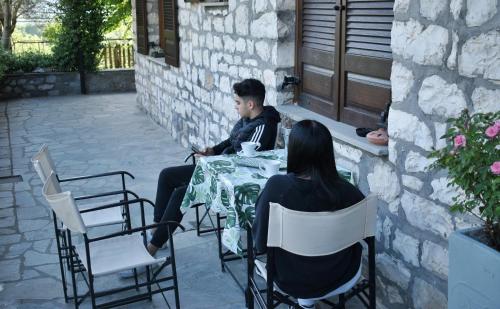 a man and a woman sitting at a table at Elichrysos GuestHouse Konitsa in Konitsa