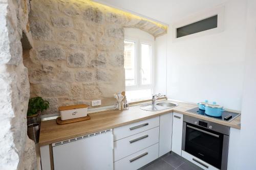 cocina con armarios blancos y pared de piedra en Contarini Apartment en Split