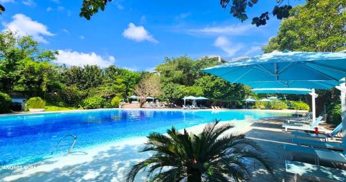 una gran piscina con sombrilla y sillas en TDJ Japandi Studio in Tambuli Seaside Living Fully Equipped, en Maribago