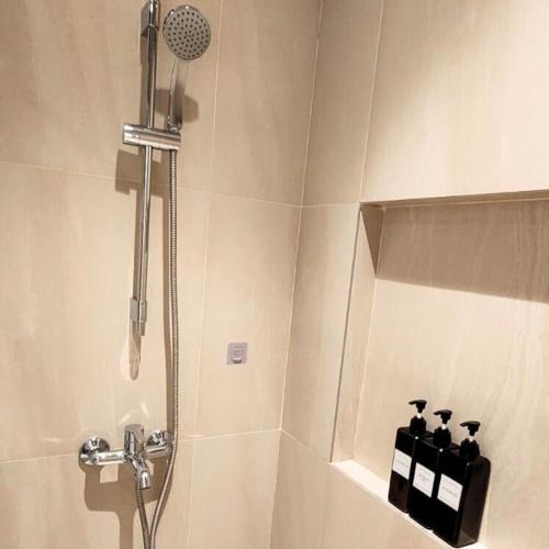 a bathroom with a shower with bottles on a shelf at TDJ Japandi Room with Residential Pool access in Tambuli Seaside Mactan in Maribago