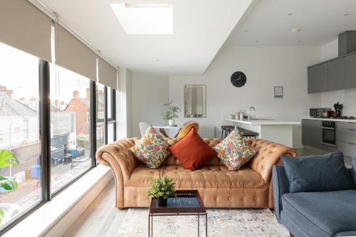 een woonkamer met een bruine bank met kussens bij Luxury Fully Equipped Kitchen Ormeau Park in Belfast