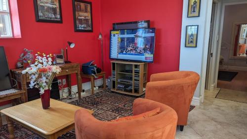 a living room with a tv and a table and chairs at Dalebrook Sea-Facing Apartment in Kalk Bay in St James